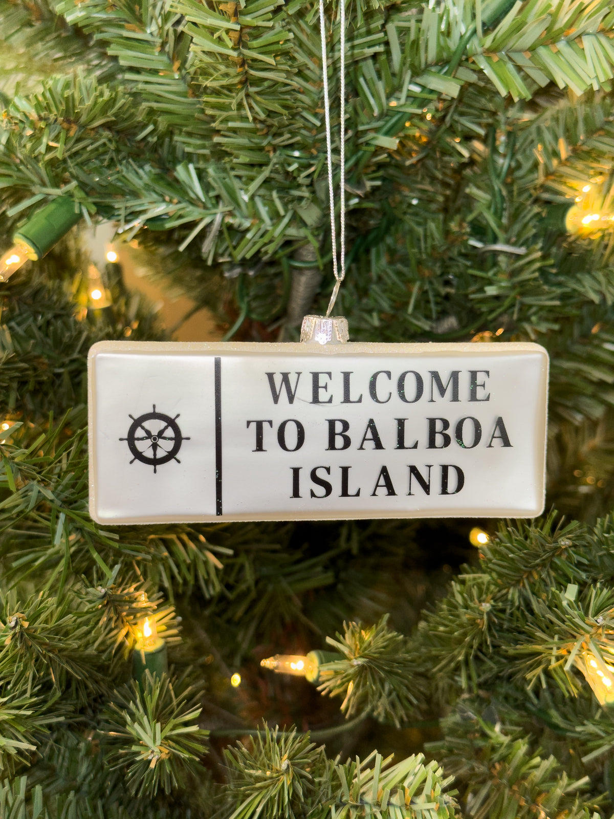 Hand-blown glass ornament of a “Welcome to Balboa Island” sign with a ship’s wheel emblem