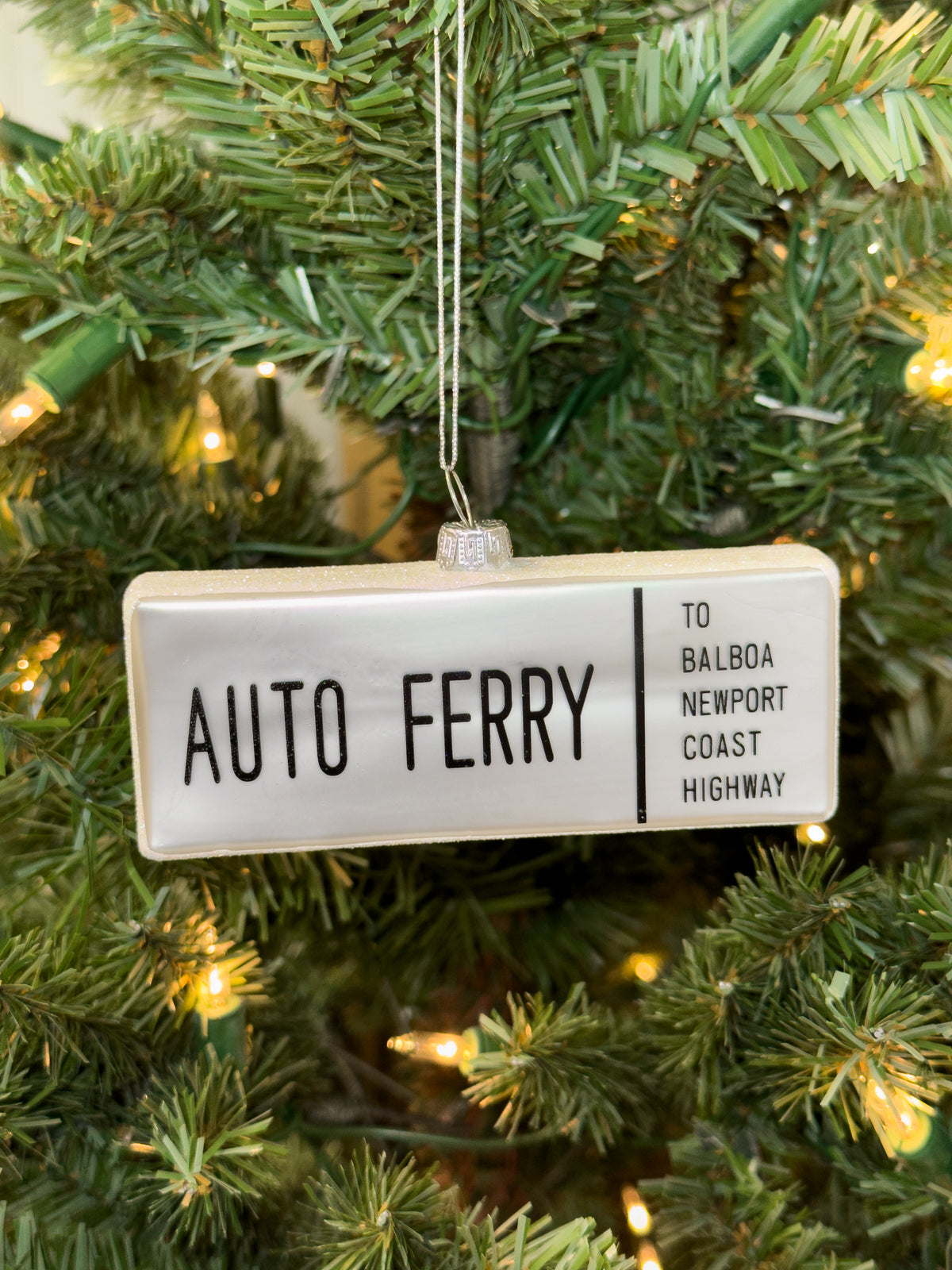 Hand-blown glass ornament of the “Auto Ferry to Balboa – Newport Coast Highway” street sign