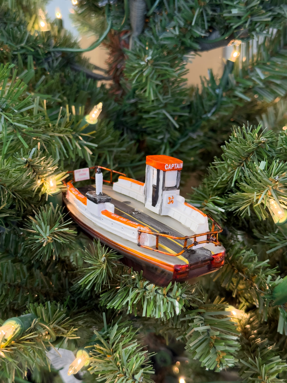 Hand-blown glass ornament of the Balboa Island auto ferry in orange and white, side view