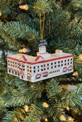 Hand-blown glass ornament of the white Hotel Laguna building with red trim and rooftop sign, front view